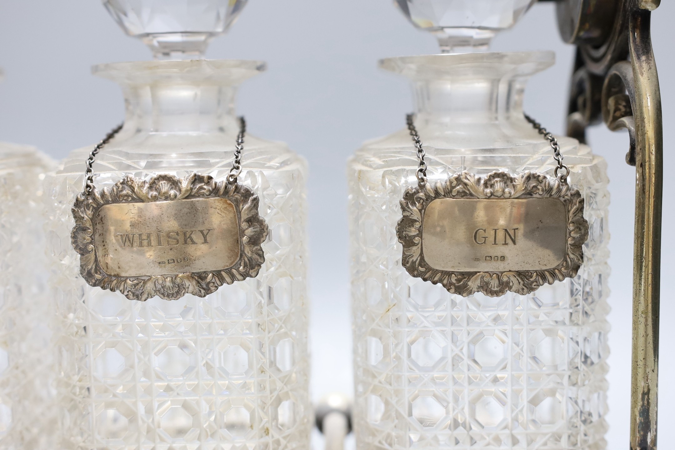 A Victorian electroplate three bottled tantalus, with a silver whisky and gin label plus pair of plated grape scissors, tantalus 33 cms wide